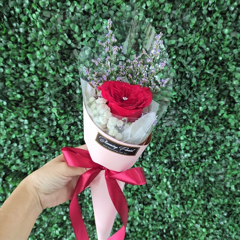 single red rose with diamond pin in a hand bouquet